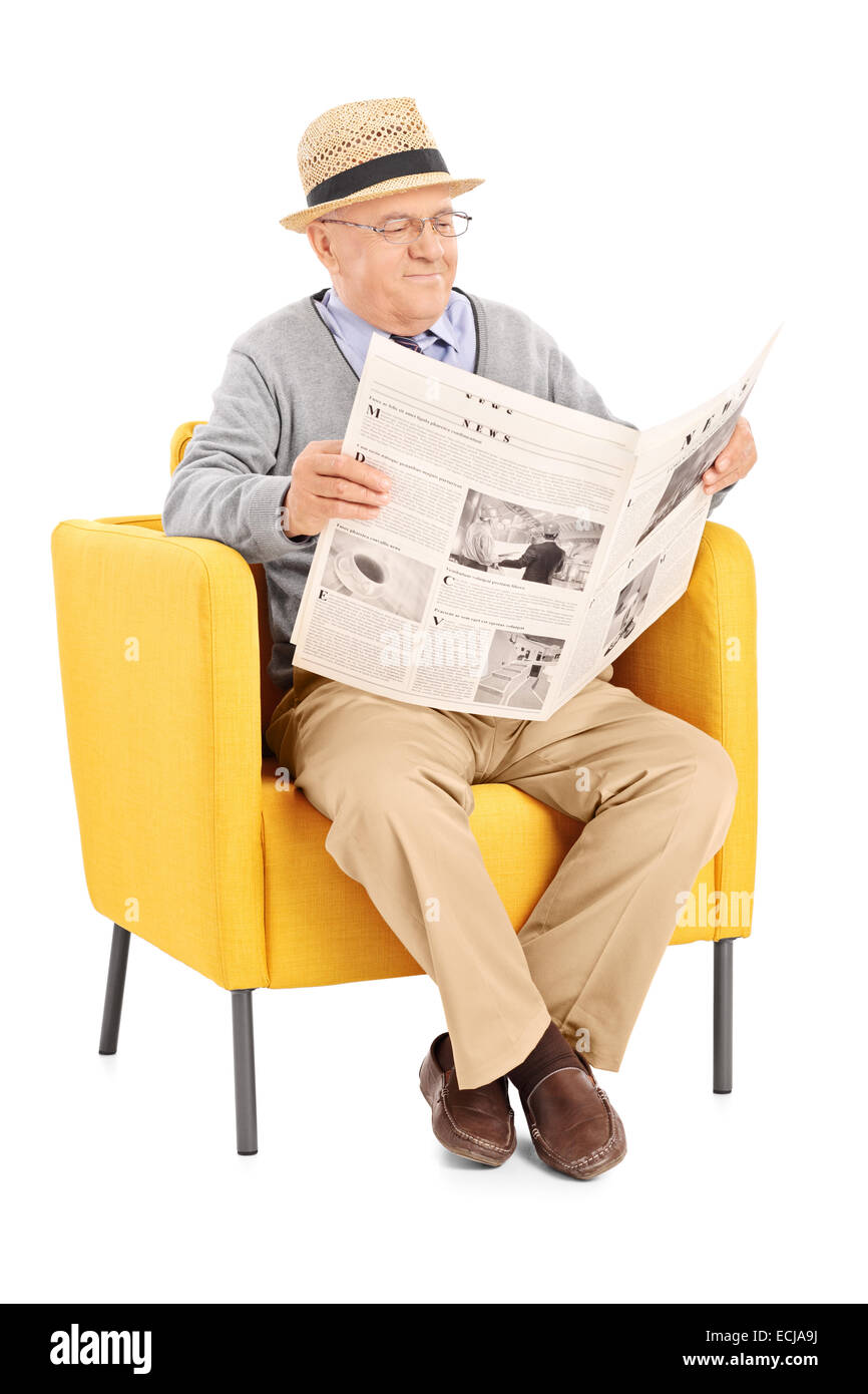 Shot vertical d'un senior de lire le journal dans un fauteuil moderne isolé sur fond blanc Banque D'Images