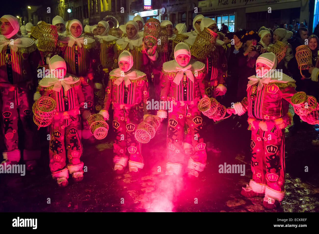 Les jeunes Gilles dansant dans la lumière d'un feu d'artifice rouge au cours d'une procession nocturne, Binche Carnaval, Binche, Belgique Banque D'Images