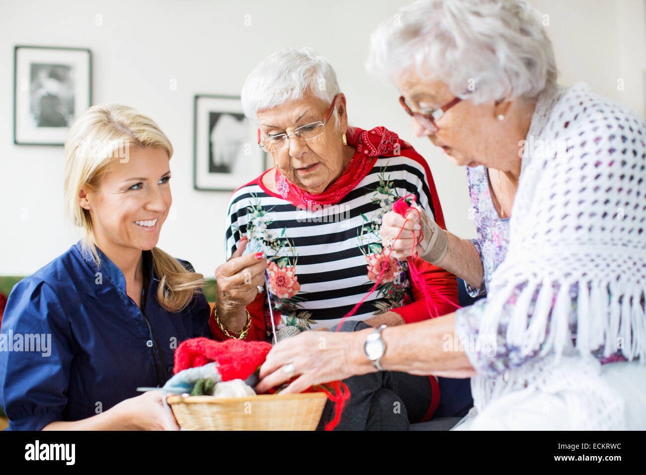 Happy female concierge à choisir des femmes aux échelons supérieurs pour le tricot de laine à la maison de soins infirmiers Banque D'Images