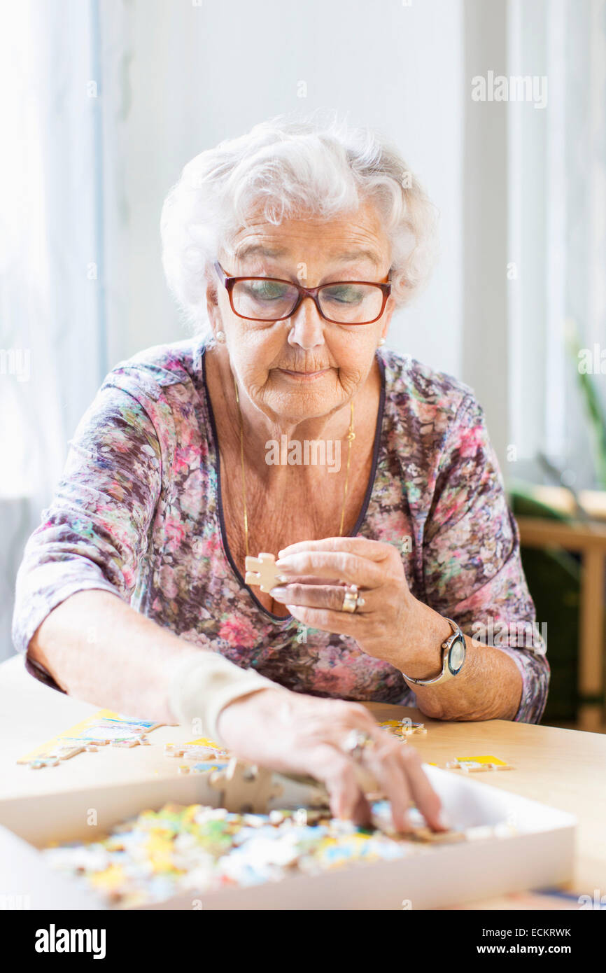 L'assemblage de pièces de puzzle Senior woman at table in nursing home Banque D'Images
