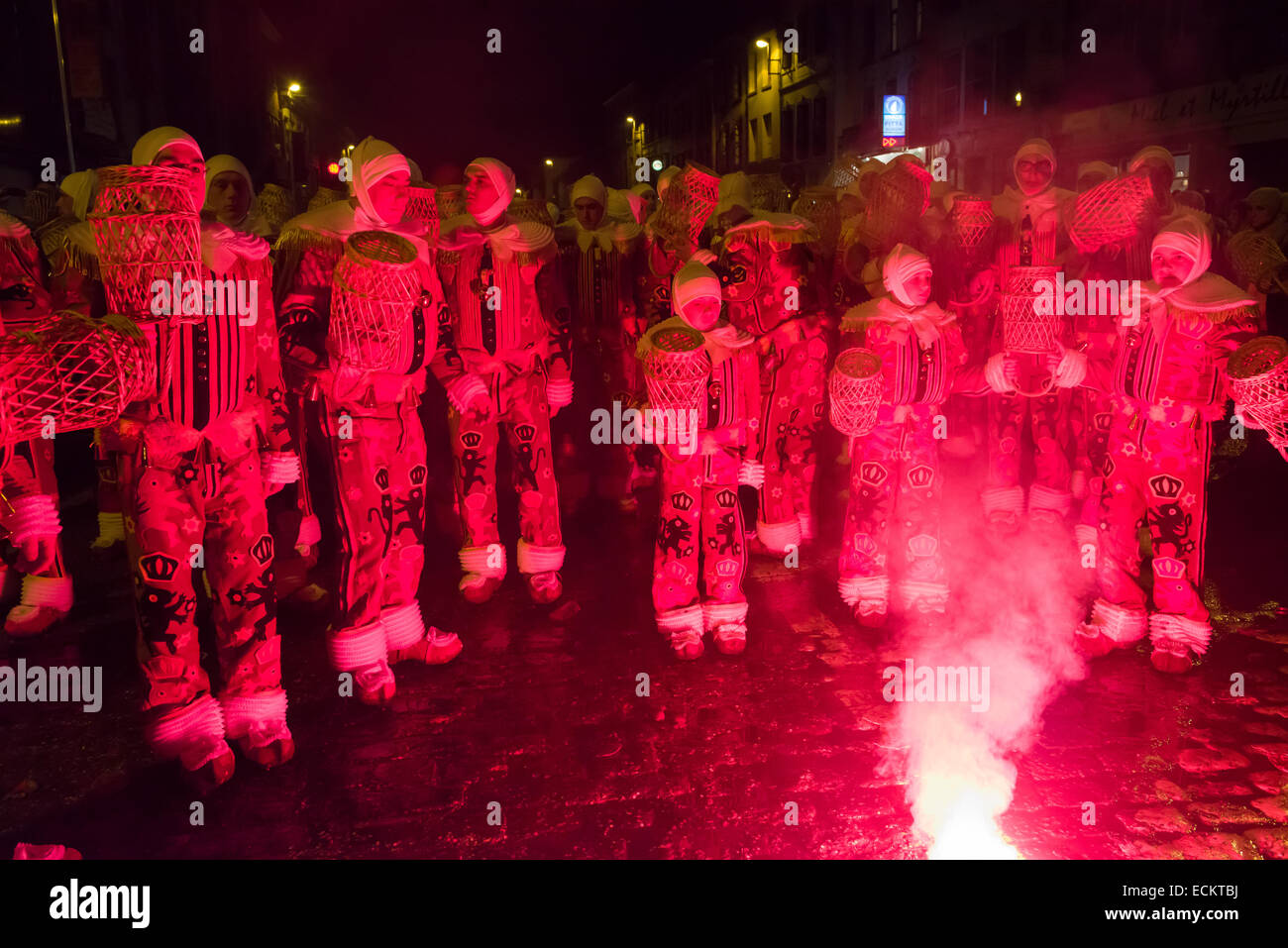 Les jeunes Gilles dansant dans la lumière d'un feu d'artifice rouge au cours d'une procession nocturne, Binche Carnaval, Binche, Belgique Banque D'Images