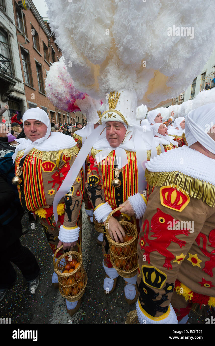 Gilles portant des coiffes d'autruche et transportant des oranges lors d'une procession dans le streetsat la Binche Carnaval, Binche, Belgique Banque D'Images