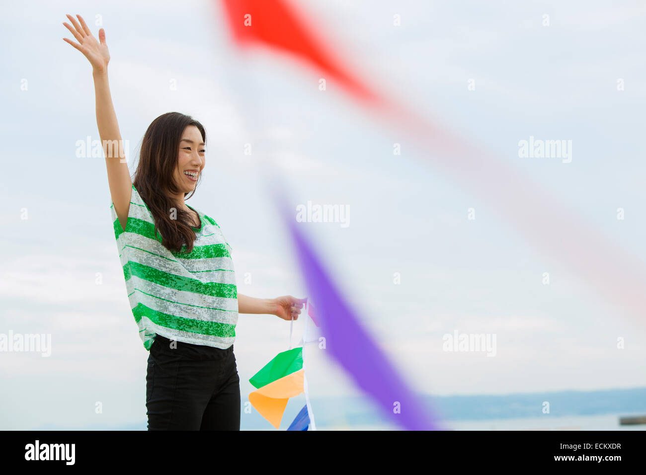 Une femme sur une plage à Kobe holding drapeaux en papier. Banque D'Images