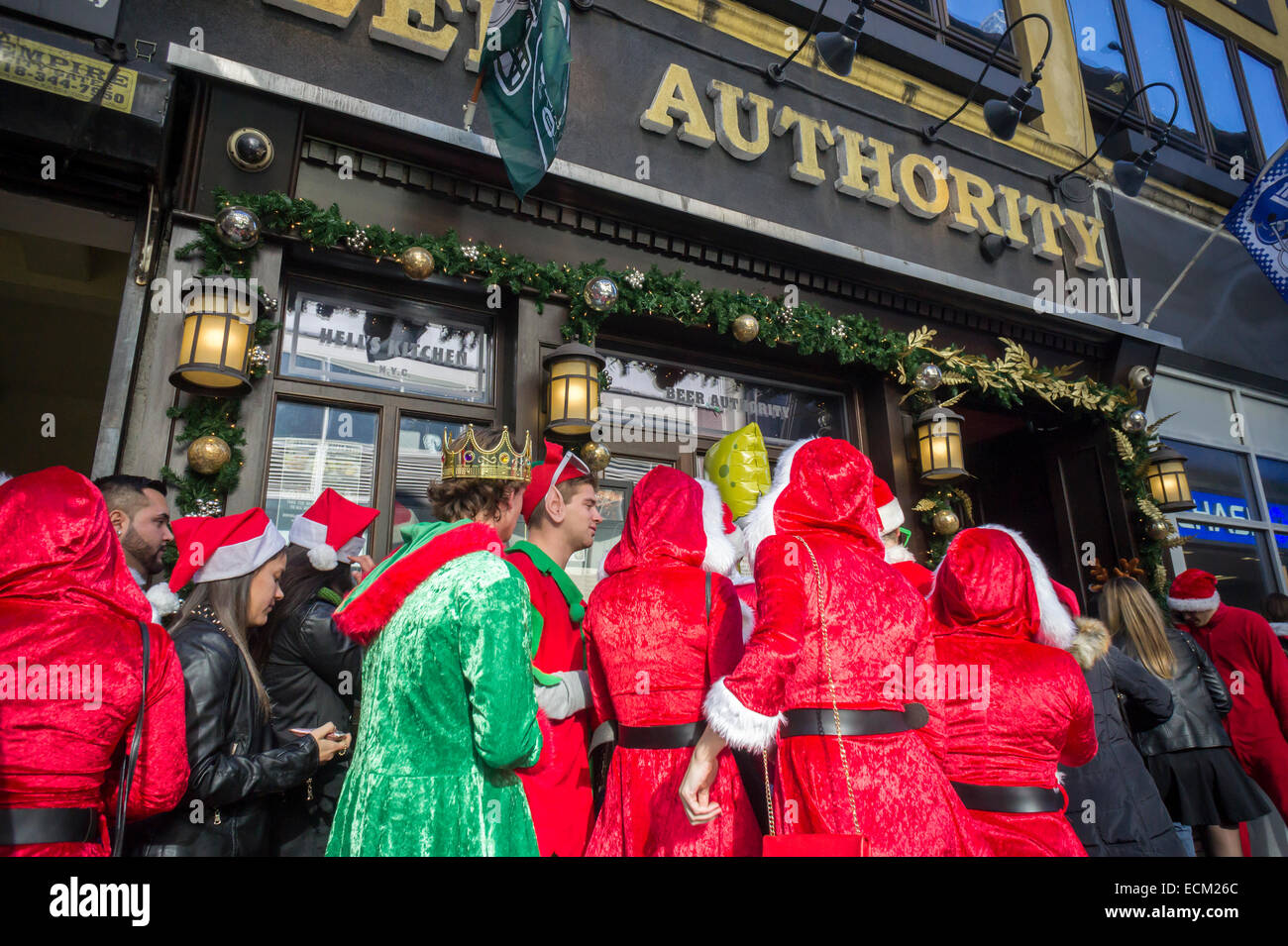 Santas et leur ligne d'elfes à l'extérieur de l'autorité de la bière au bar de Midtown à New York au cours de la SantaCon annuelle le samedi, Décembre 13, 2014. SantaCon, principalement un pub crawl à Santa et d'autres connexes Noël costumes, attire des milliers de masqueraders allant de bar en bar. Cette année en raison de repousser à partir de différents quartiers SantaCon est plus faible et les organisateurs encouragent un comportement approprié. (© Richard B. Levine) Banque D'Images