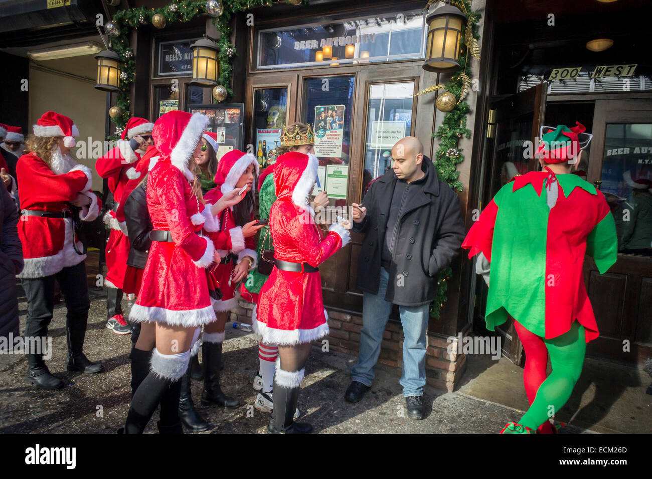 Un portier à l'extérieur de l'autorité de la bière dans un bar à New York Midtown vérifie l'identité et l'âge des clients au cours de l'Assemblée SantaCon le Samedi, Décembre 13, 2014. SantaCon, principalement un pub crawl à Santa et d'autres connexes Noël costumes, attire des milliers de masqueraders allant de bar en bar. Cette année en raison de repousser à partir de différents quartiers SantaCon est plus faible et les organisateurs encouragent un comportement approprié. (© Richard B. Levine) Banque D'Images