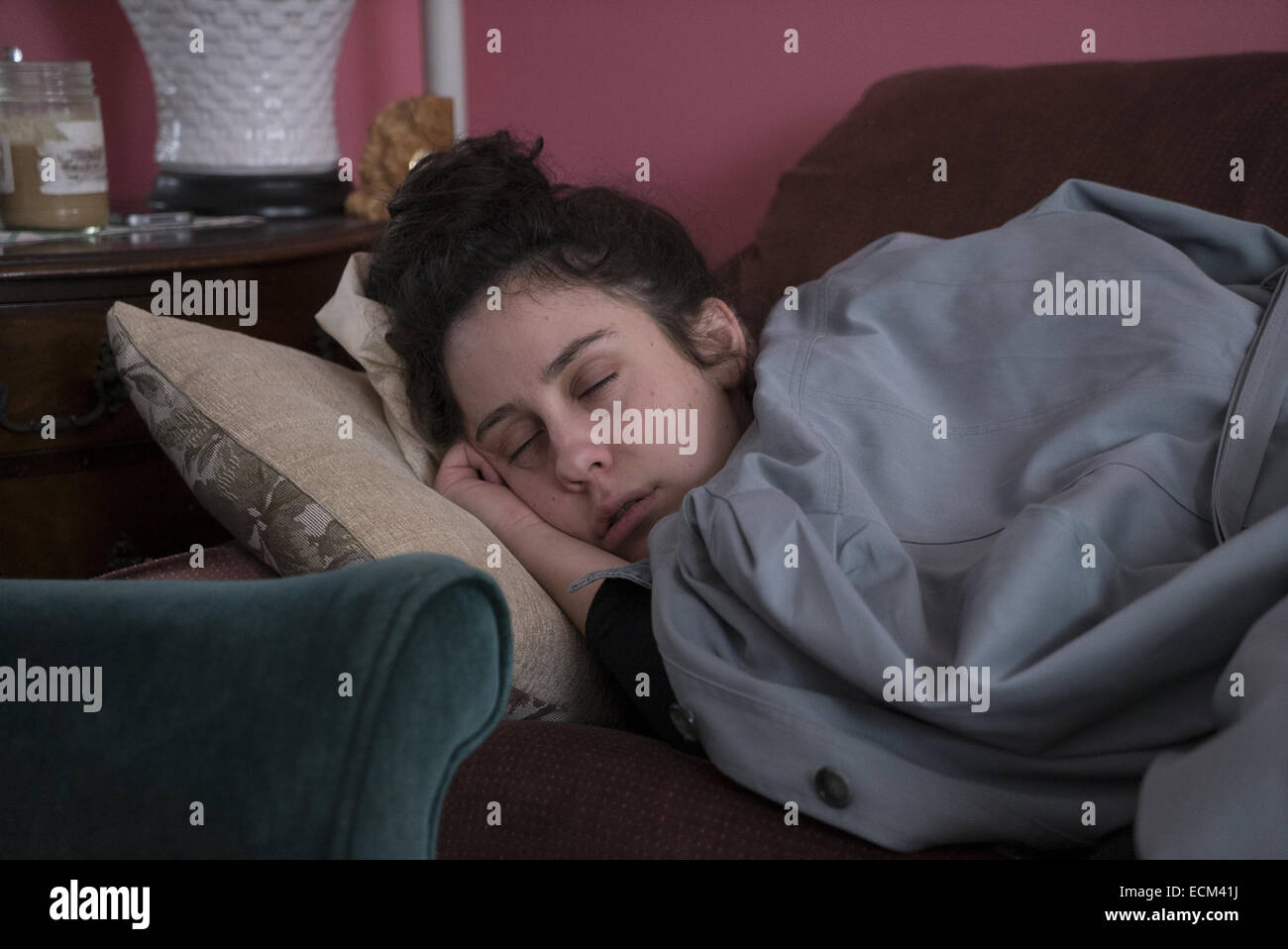 Jeune femme prend une sieste avec son manteau sur elle. Brooklyn, New York. Banque D'Images