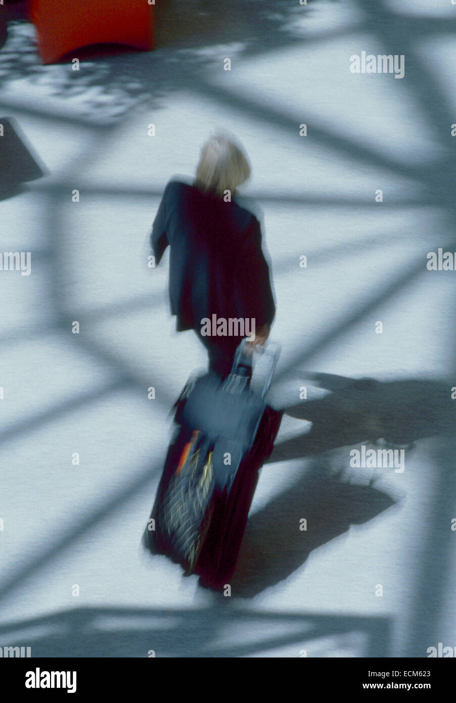 Business man in motion blur pendant qu'il marche dans une pièce lumineuse de l'atrium de l'aéroport. Banque D'Images