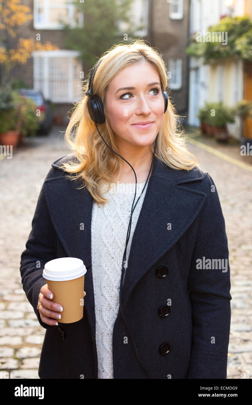 Young woman listening to music avec un café Banque D'Images