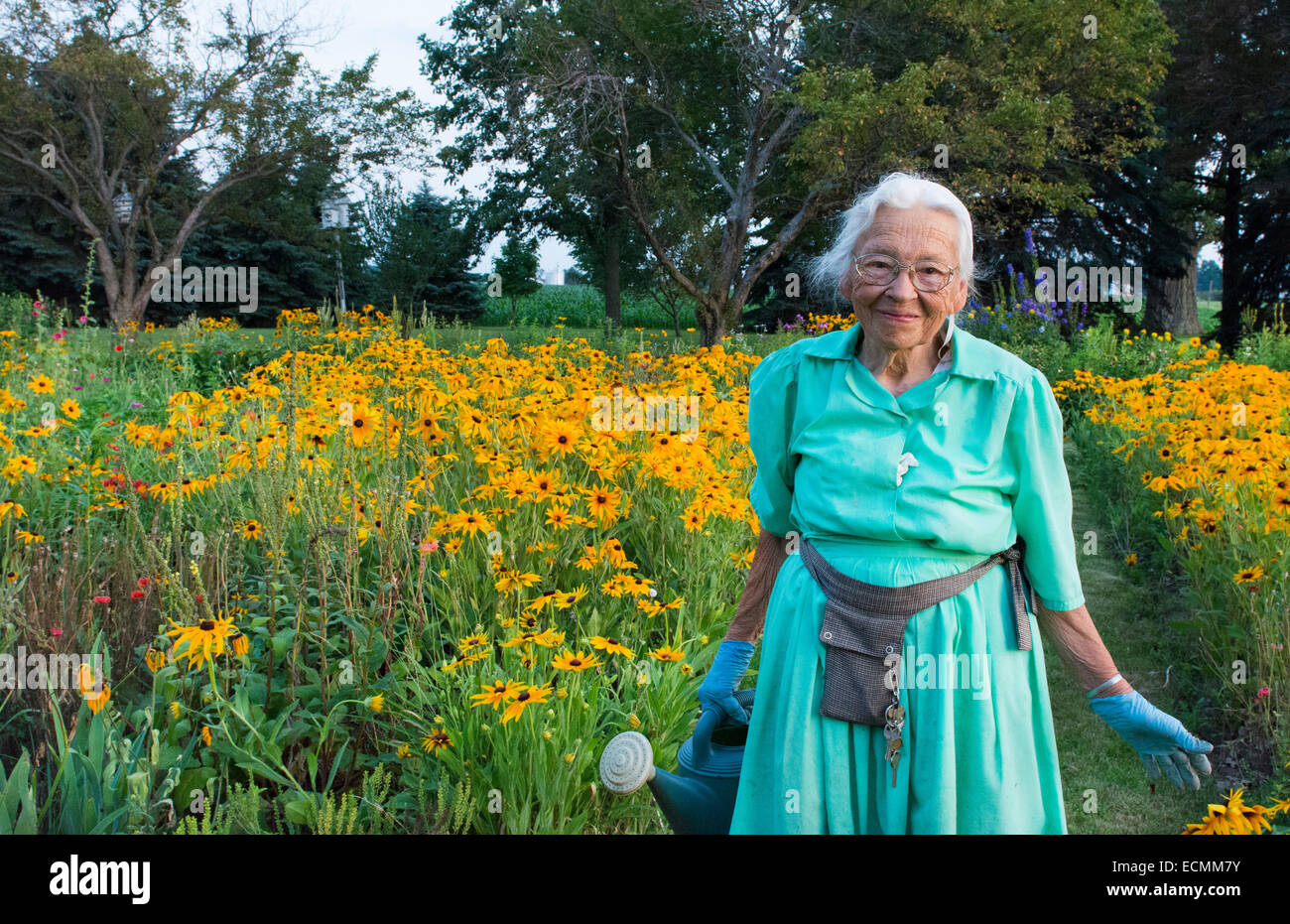 Plain City Ohio Amish 89 ans grand-mère d'arroser son jardin en fleurs à  Midwest USA en robe et sourire Photo Stock - Alamy