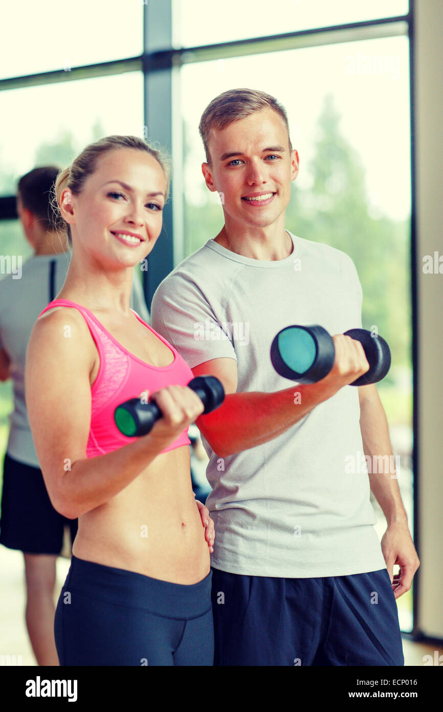Smiling young woman with personal trainer in gym Banque D'Images