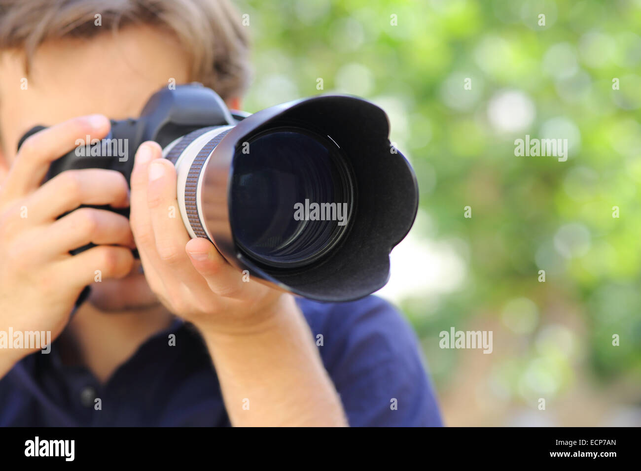Portrait d'un photographe à l'aide d'un appareil photo reflex numérique avec un fond vert Banque D'Images