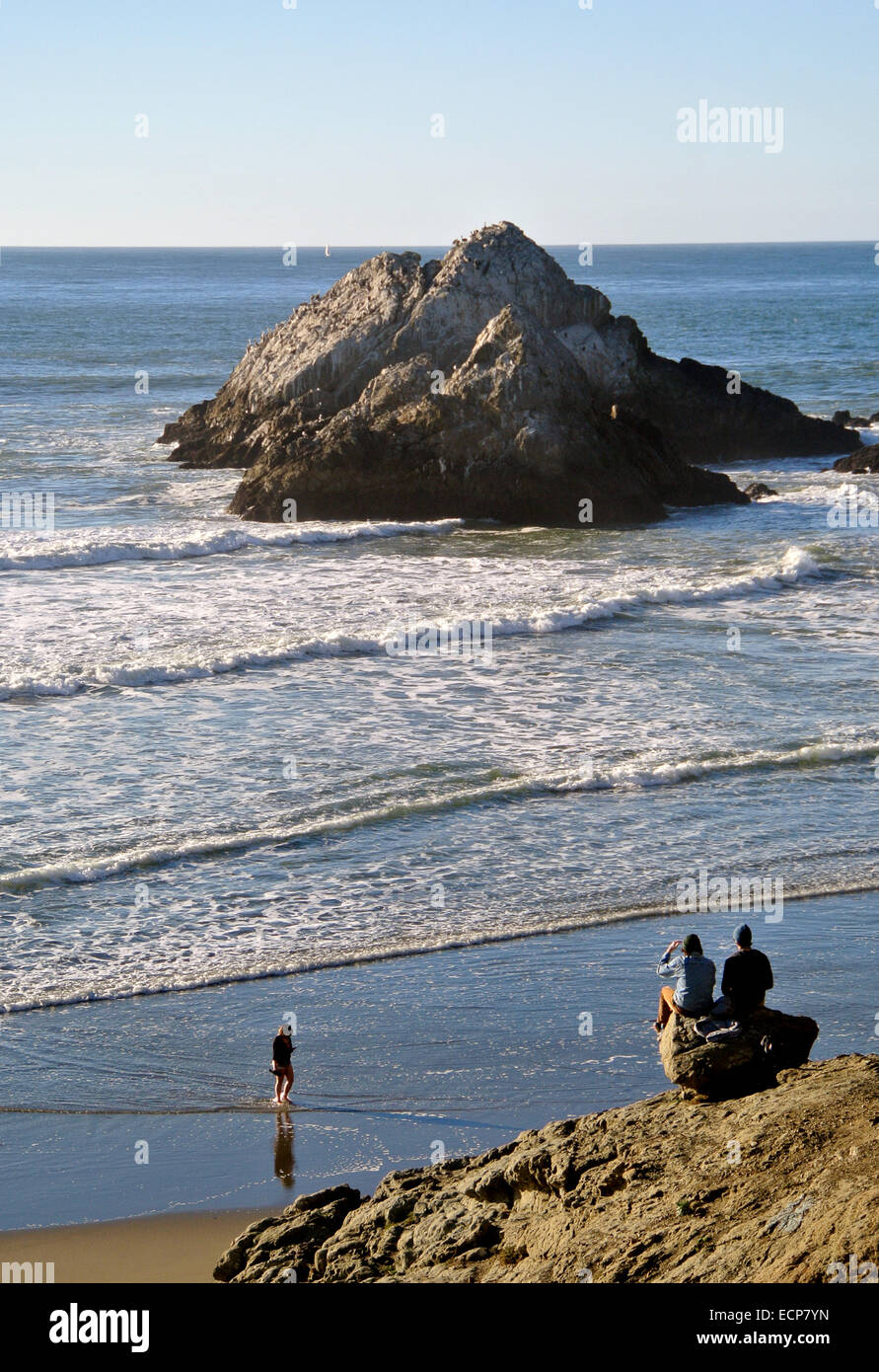 Couple d'amis regarder les vagues en rouleaux sur Ocean Beach, près de Seal Rock ci-dessous l'historique Cliff House sur la côte de Californie Banque D'Images