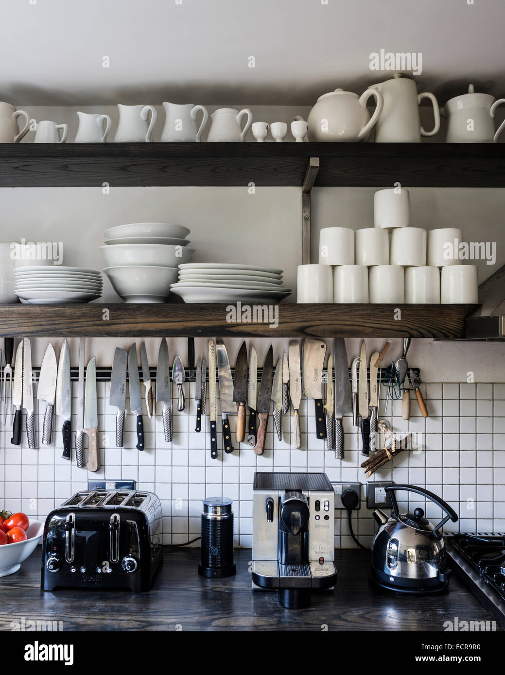 Vaisselle blanche sur des rayonnages ouverts au-dessus de la cuisine avec surface de travail de rack de couteau, grille-pain et bouilloire Banque D'Images