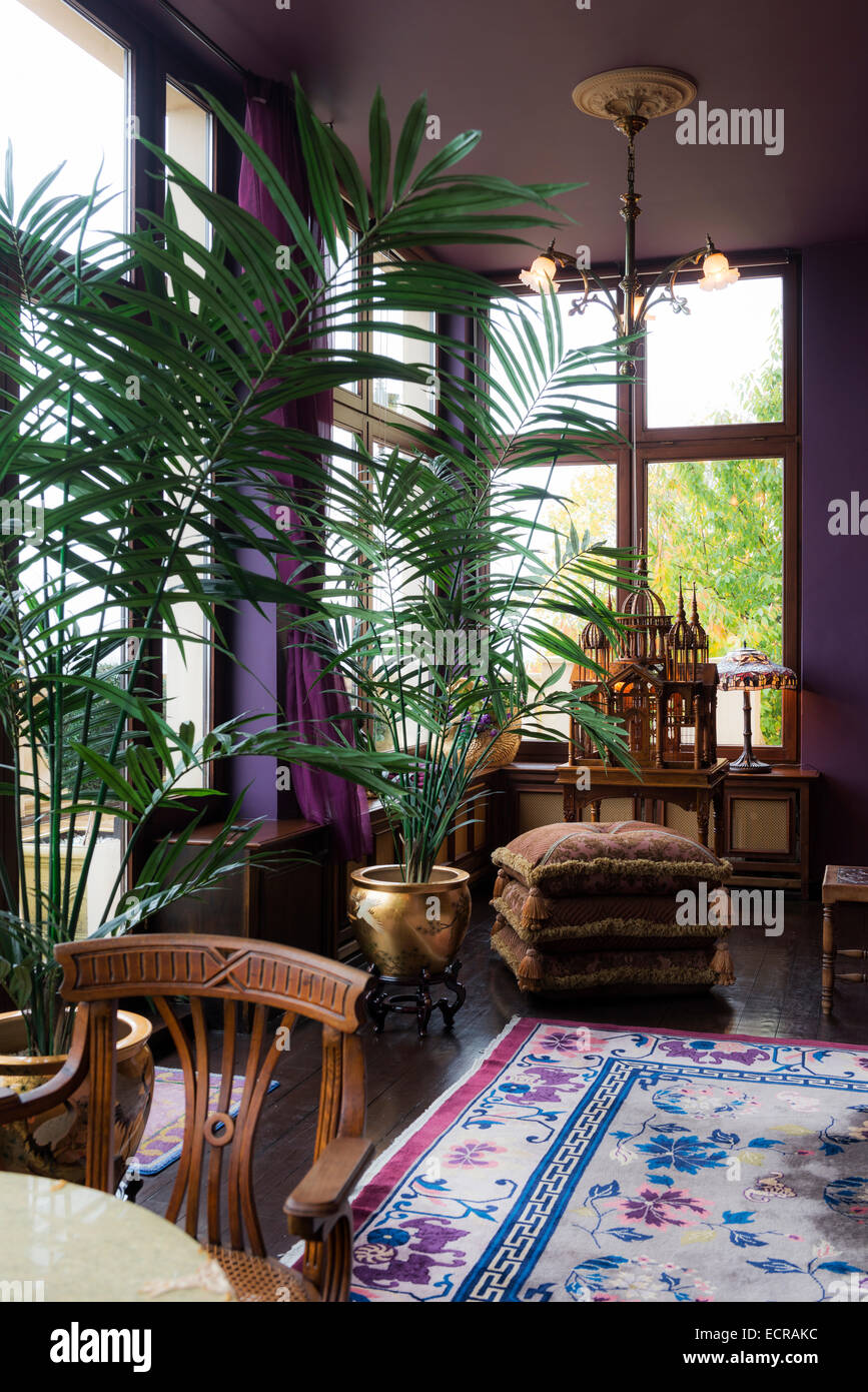 Dans l'or en pot Palms met en violet salon avec tapis et coussins empilés Banque D'Images