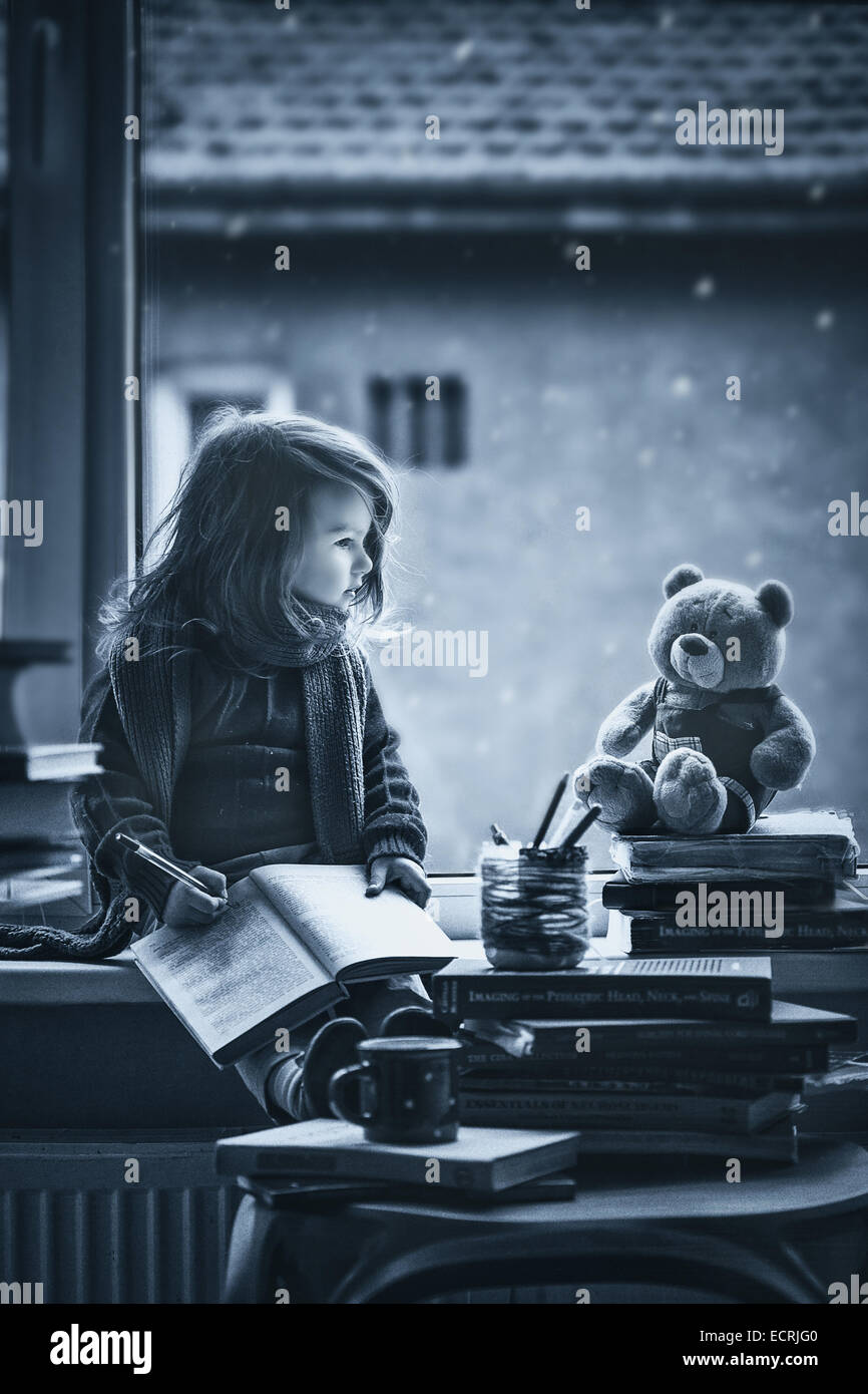 Adorable petite fille, l'écriture lettre au père, assis sur une fenêtre, livres et ours autour de Banque D'Images
