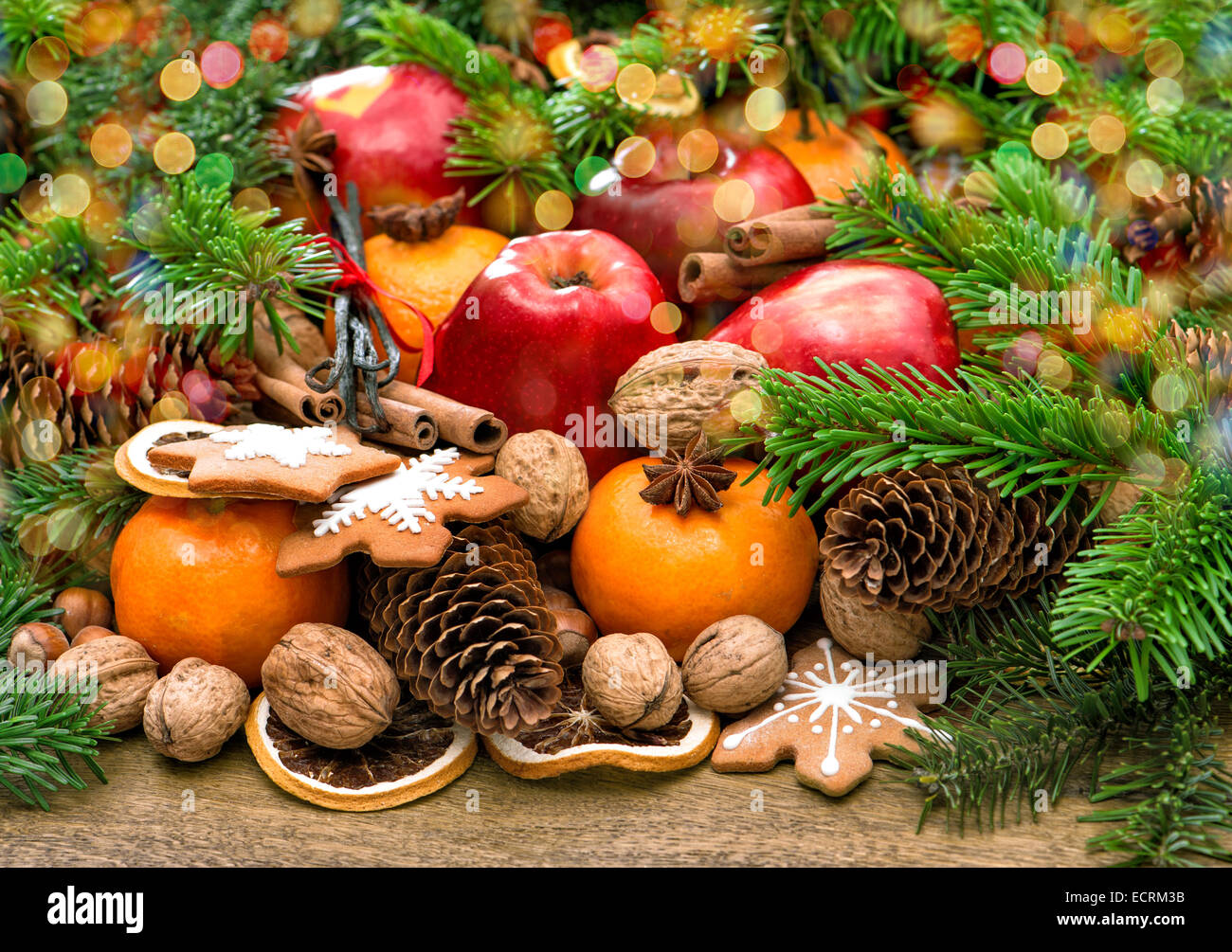 Les fruits, les noix, les biscuits et les épices avec des branches d'arbre de Noël. Repas de fête avec de belles lumières de couleur d'arrière-plan Banque D'Images