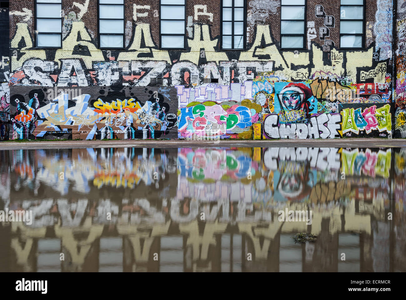 Graffiti sur un bâtiment reflète dans l'eau Banque D'Images