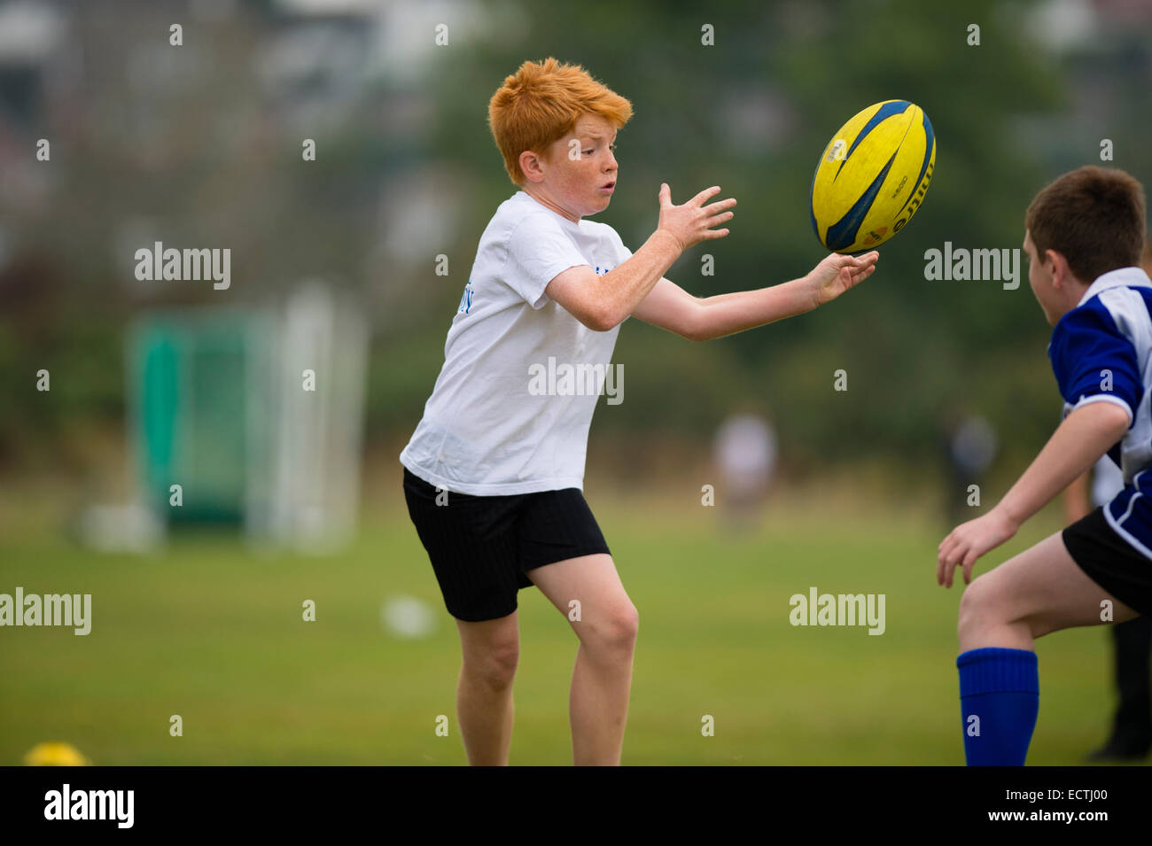 L'école secondaire de l'éducation physique PE - Pays de Galles UK : jeux leçon - les jeunes garçons adolescents passer la balle à jouer au rugby rugger en plein air sur un terrain de sport terrain de pas Banque D'Images
