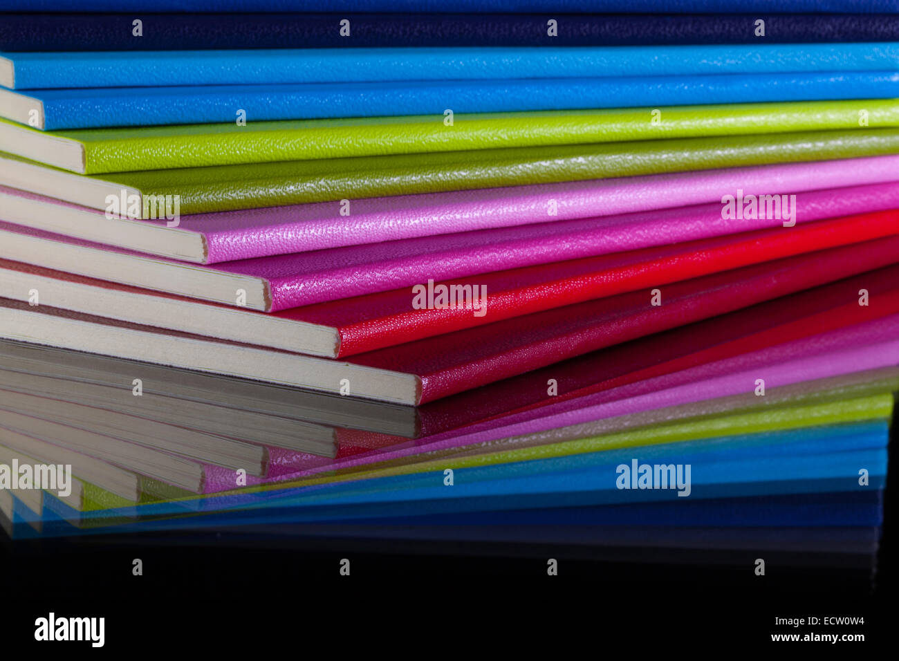 Douze journaux de différentes couleurs sur un bureau en verre Banque D'Images
