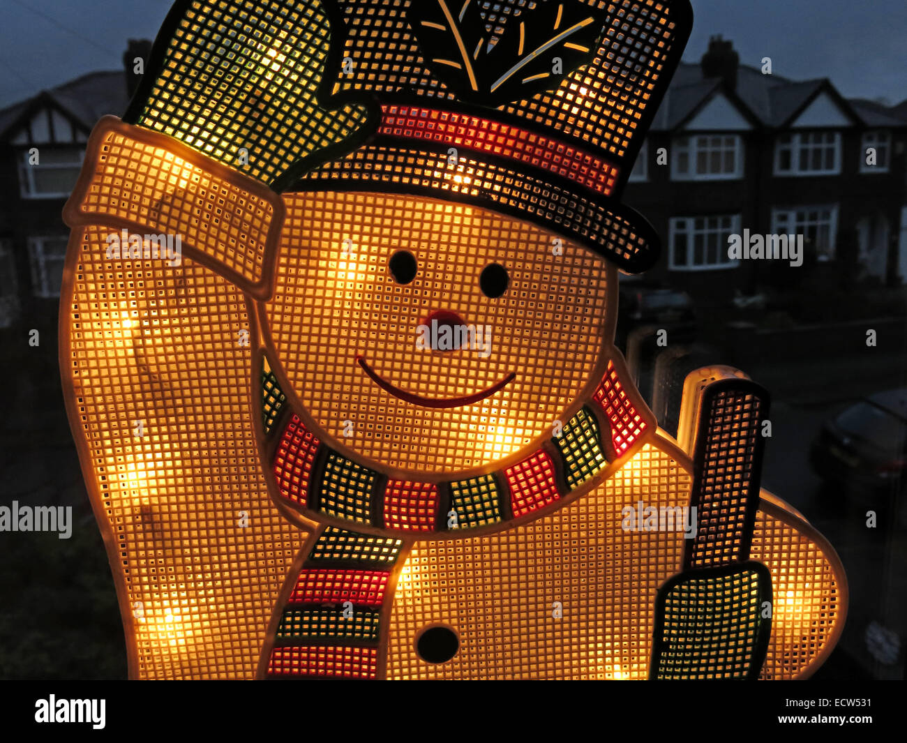 Un bonhomme de neige électrique sur une fenêtre, illuminé pour Noël Banque D'Images