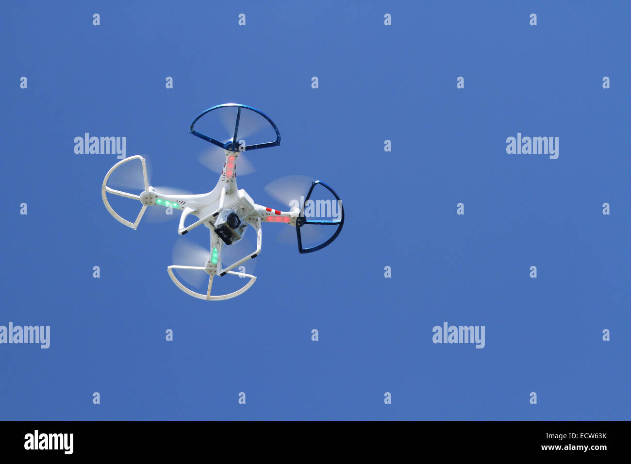 Quadcopter. Quadracopter. Drone. Avec caméra vidéo jointe. Voir, à partir du dessous pendant le vol. Contre le ciel bleu. Banque D'Images