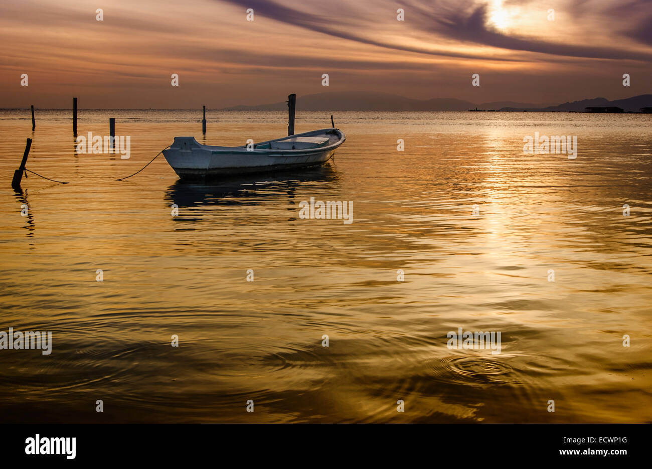 Un seul bateau de pêche attendre le coucher du soleil, majestueux nuages dans le ciel Banque D'Images