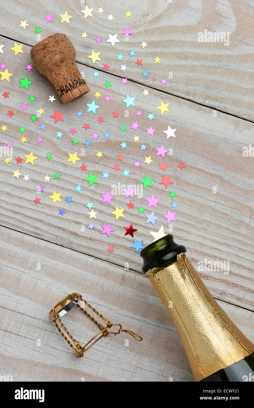 Passage d'une bouteille de champagne avec le liège apparaissant sur une table en bois rustique. Le jet de la bouteille est dans la forme de colo Banque D'Images