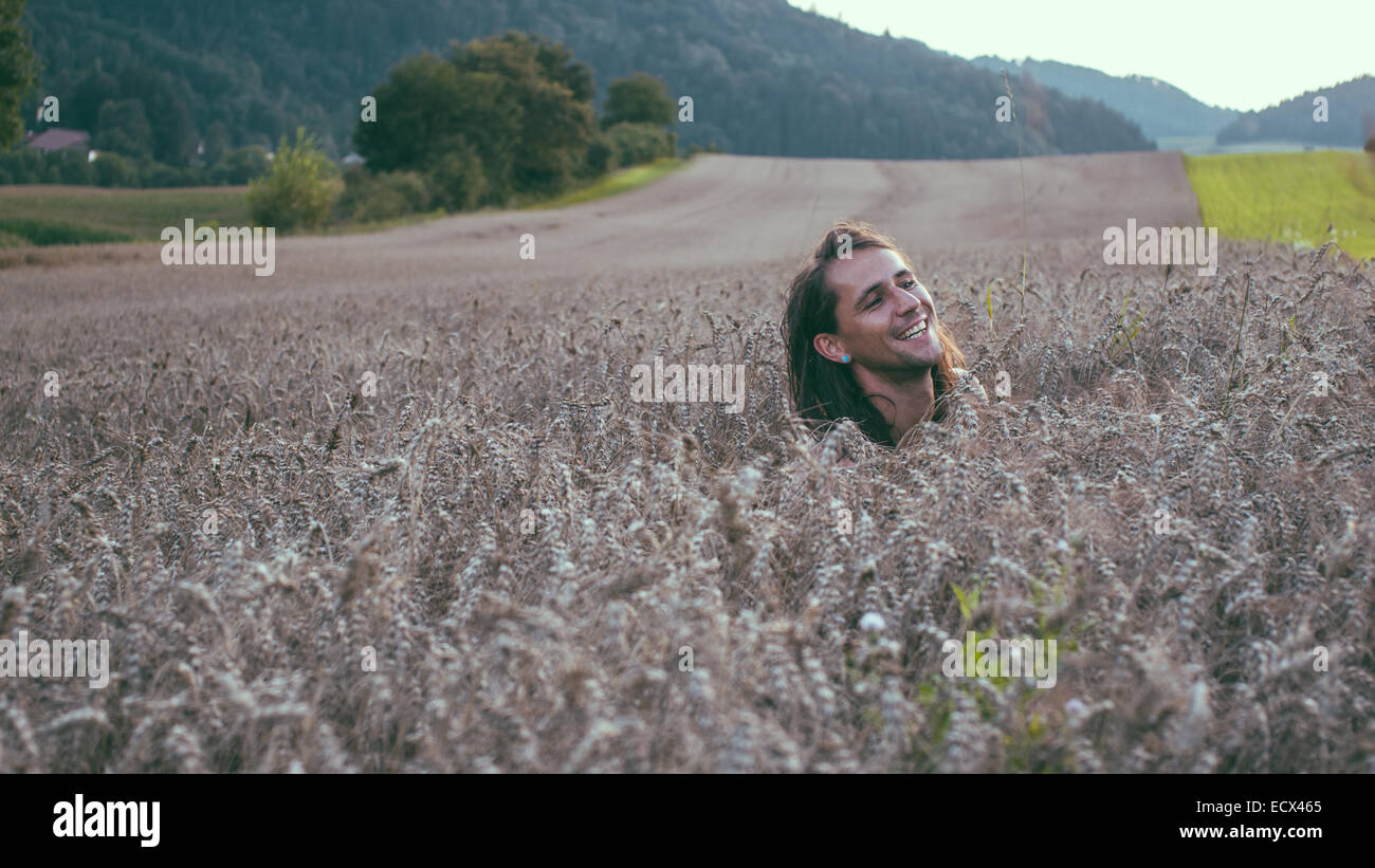 Bel homme en champ de blé, qui sort de la tête et il rit. Banque D'Images