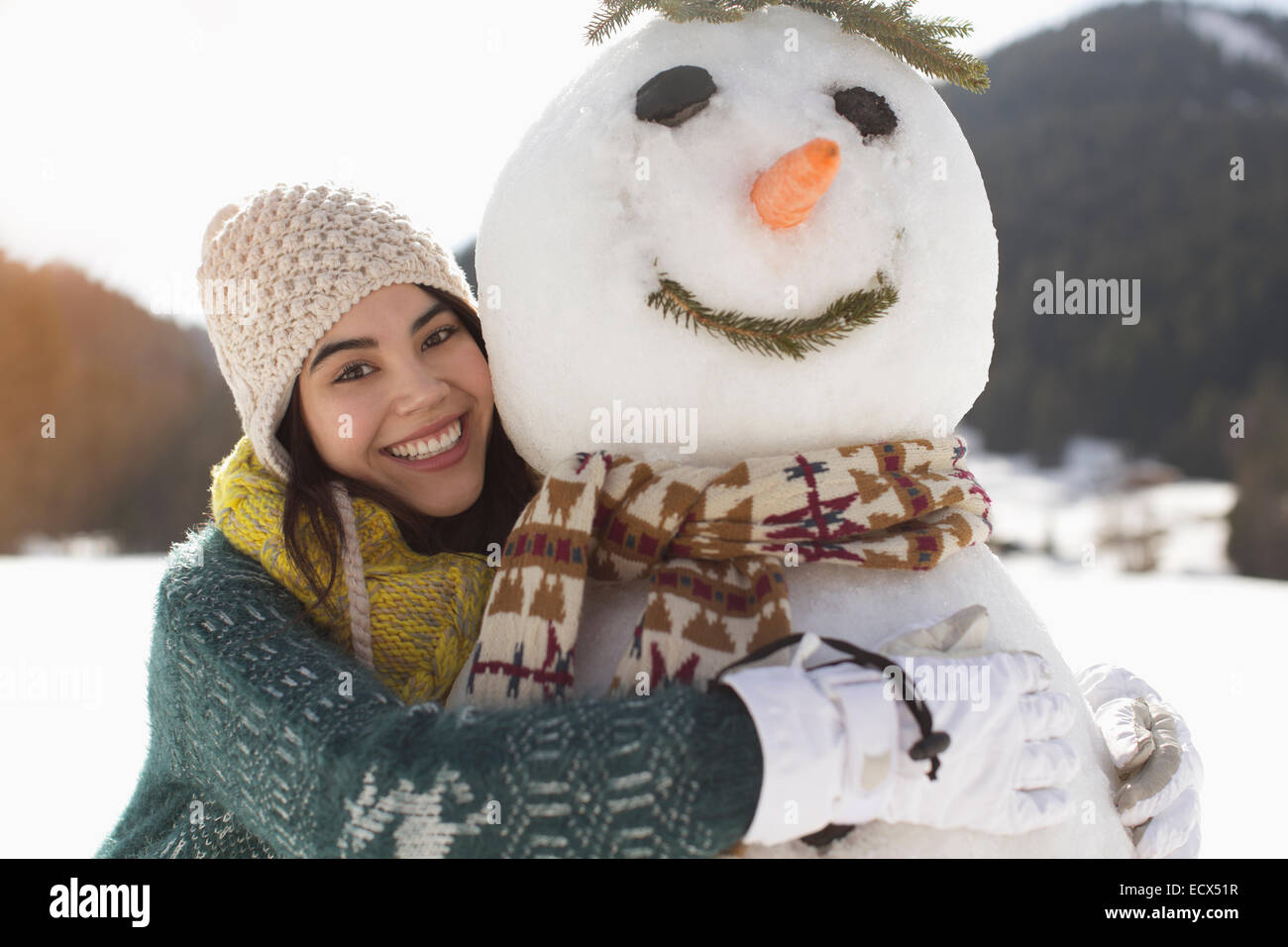Portrait of smiling woman hugging snowman Banque D'Images