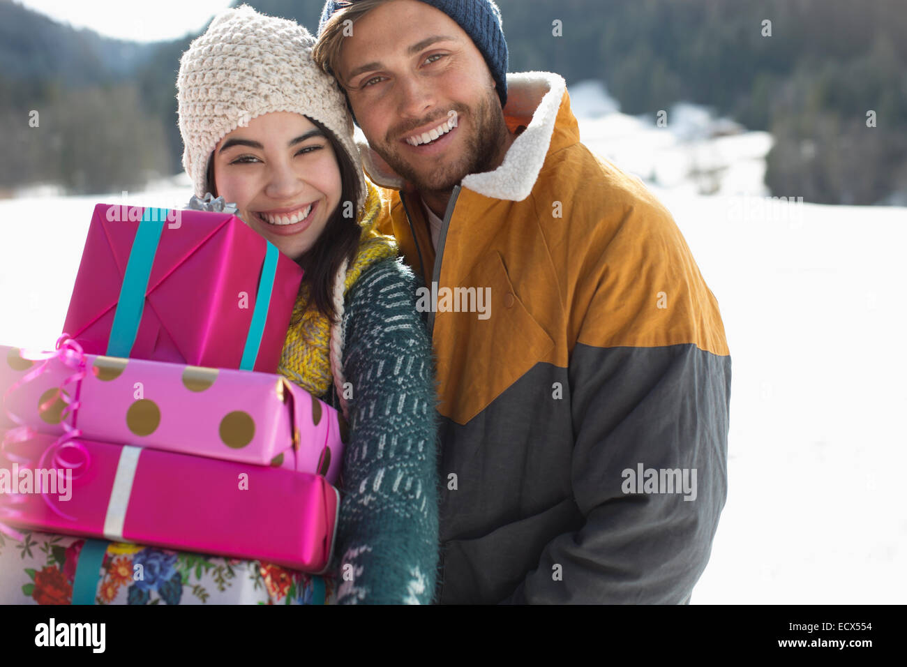 Portrait of smiling couple with Christmas gifts in snow Banque D'Images