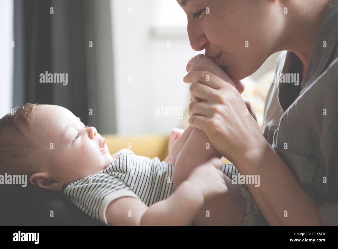 Mother holding et d'embrasser les pieds du bébé peu Banque D'Images