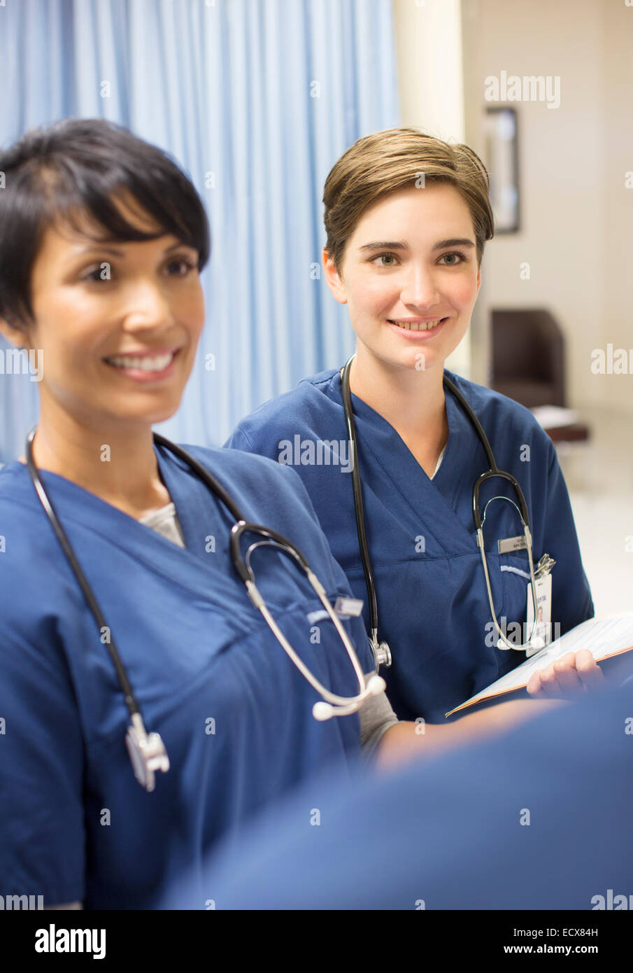 Deux smiling doctors wearing scrubs avec stéthoscope autour de cou à l'hôpital Banque D'Images