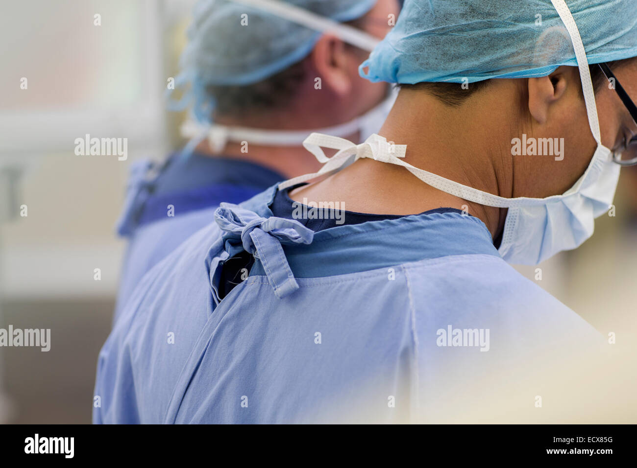 Les médecins portant des masques chirurgicaux, caps et frotte en salle d'opération Banque D'Images