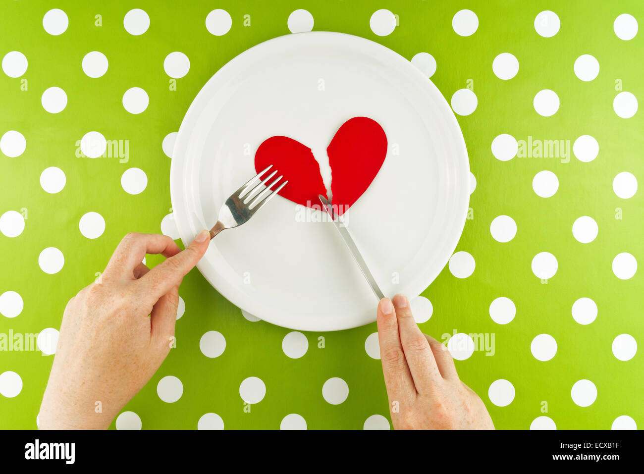 Woman eating cœur brisé sur une plaque blanche, vue du dessus. Banque D'Images