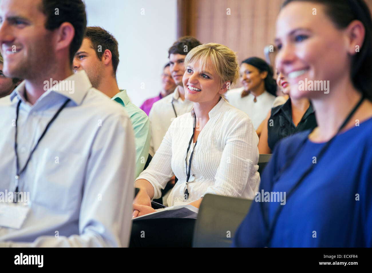 Portrait of smiling woman sitting dans la salle de conférence, avec l'homme et la femme dans l'avant-plan flou Banque D'Images