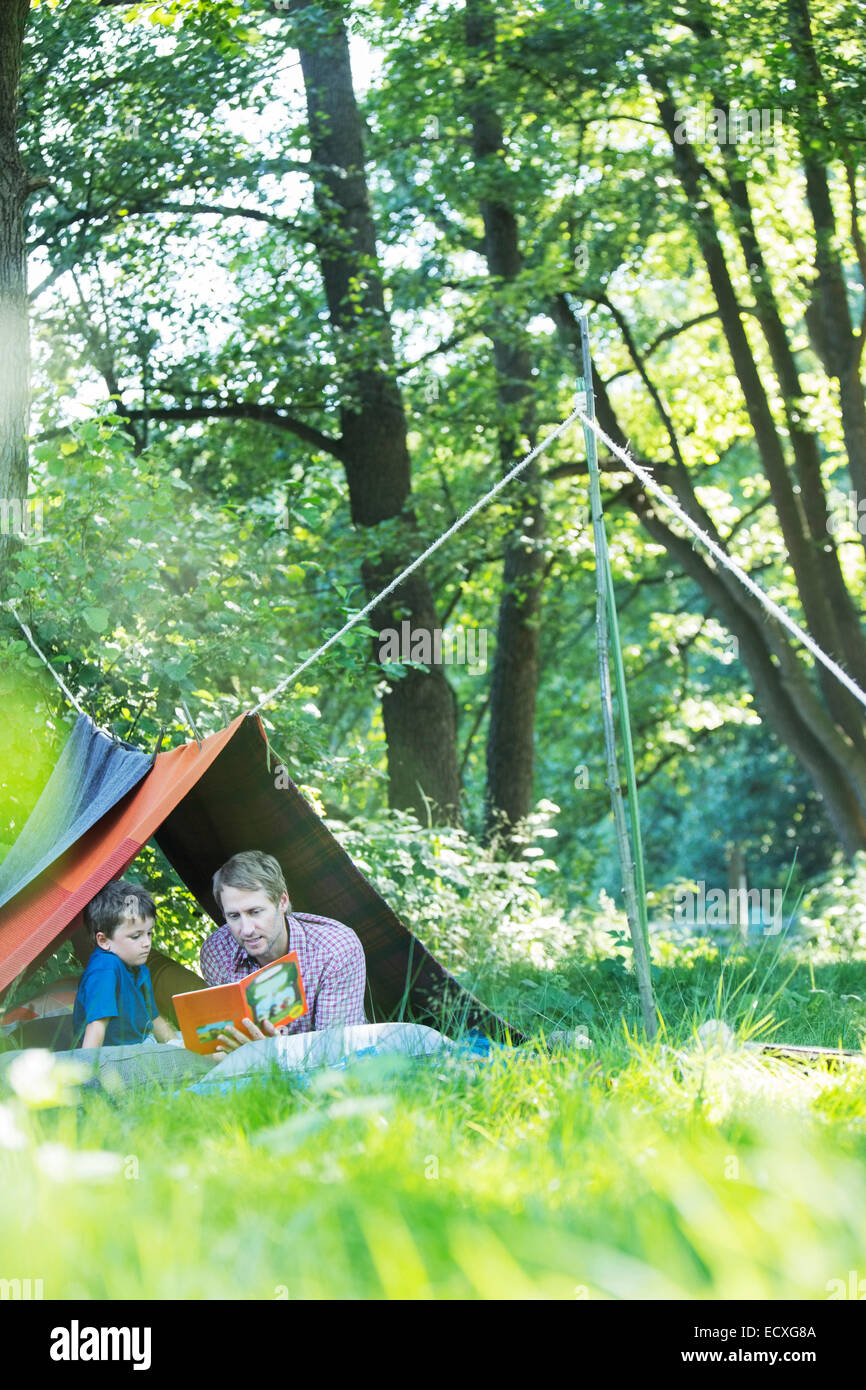 Père et fils en lecture tente de camping Banque D'Images