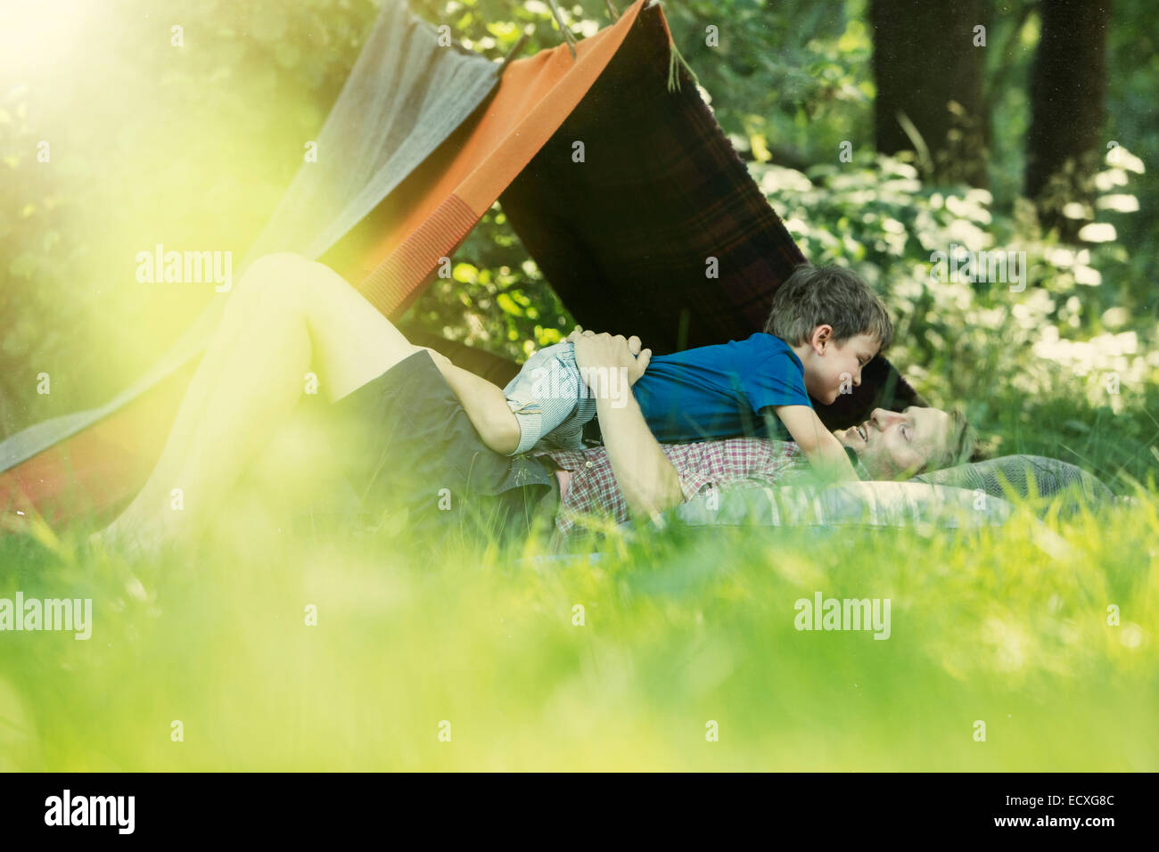 Père et fils laying in grass près de tente de camping Banque D'Images