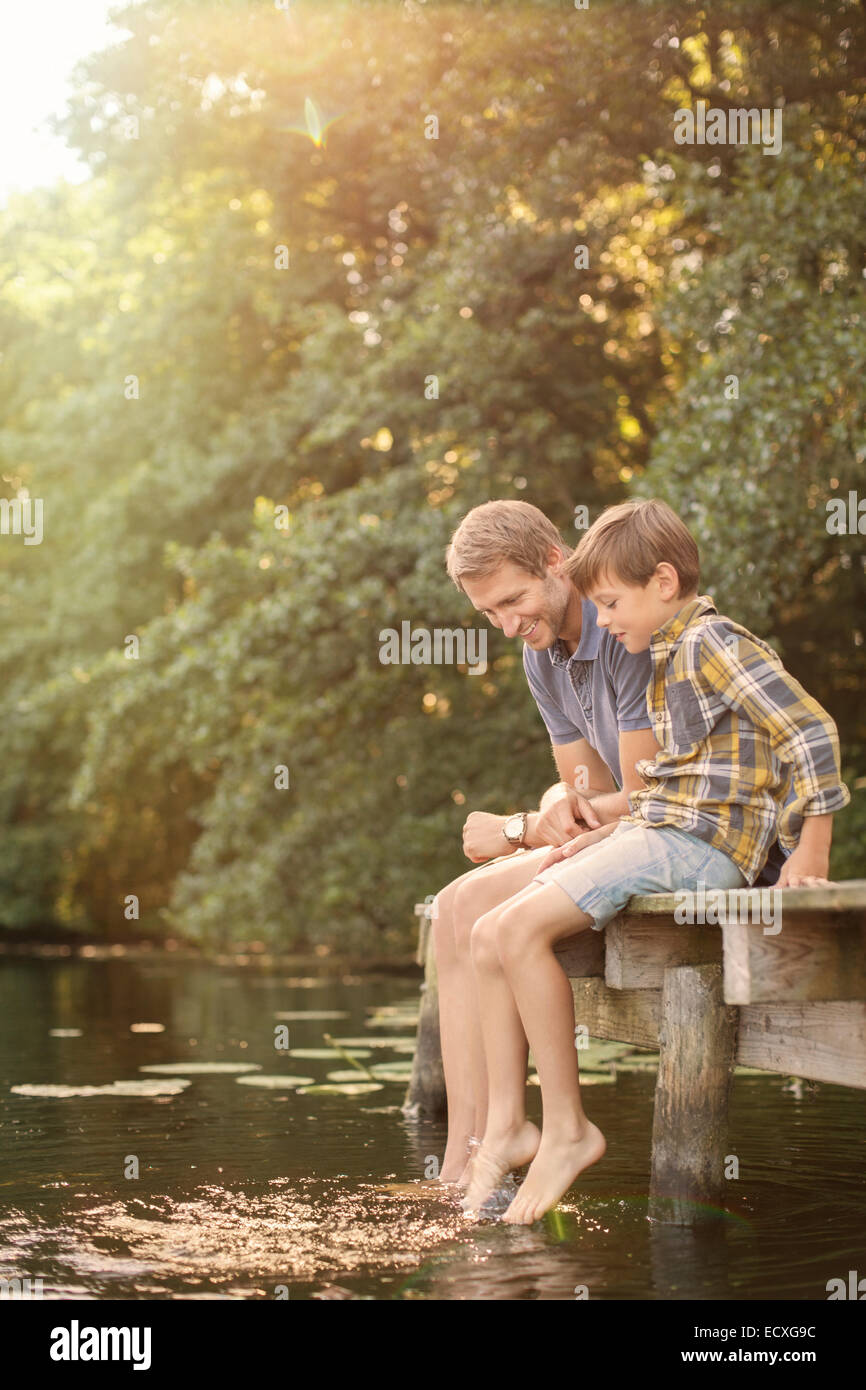 Père et fils pieds ballants dans le lac Banque D'Images