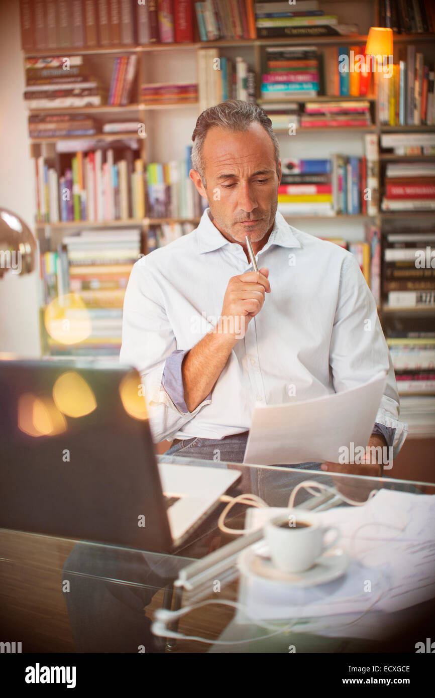 Businessman reading paperwork at home office 24 Banque D'Images
