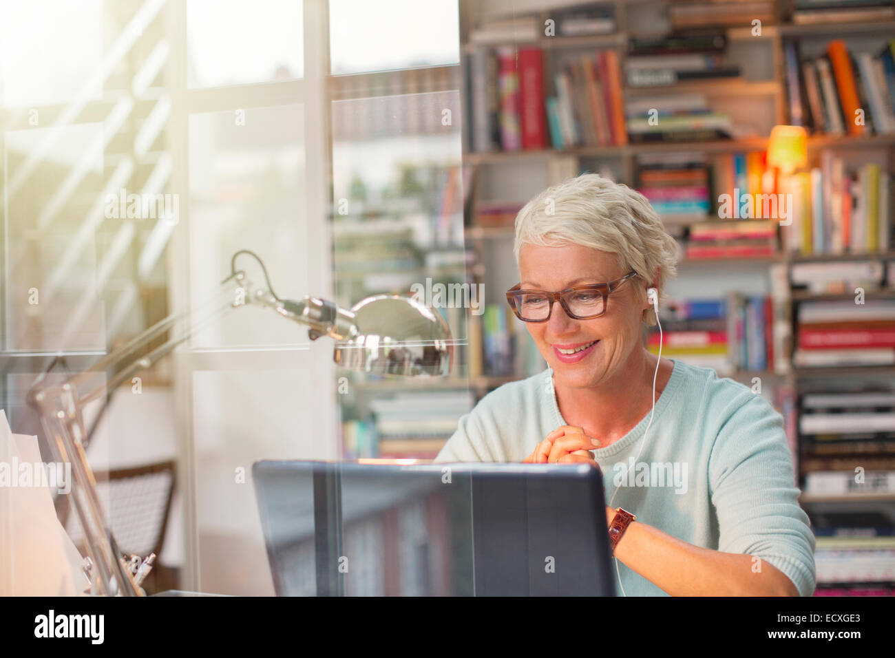 Businesswoman listening to oreillettes et travaillant en home office Banque D'Images