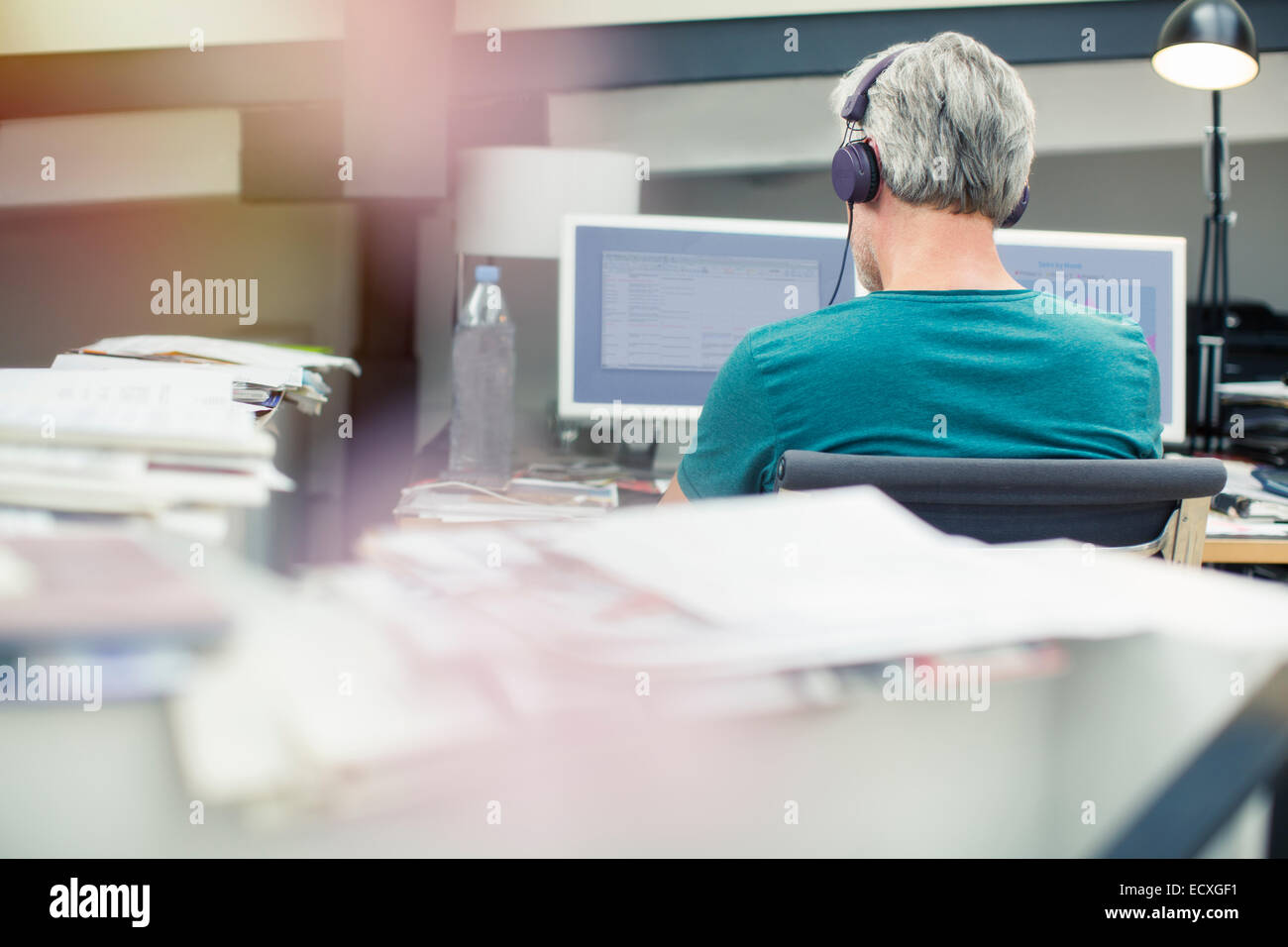 Woman listening to headphones in office Banque D'Images