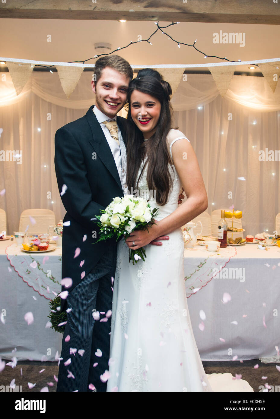 Mariage / Wedding Day UK : l'heureux jeune couple bien mince mariée et le marié qui pose pour des photographies d'une pluie de confettis à leur parti d'accueil Banque D'Images