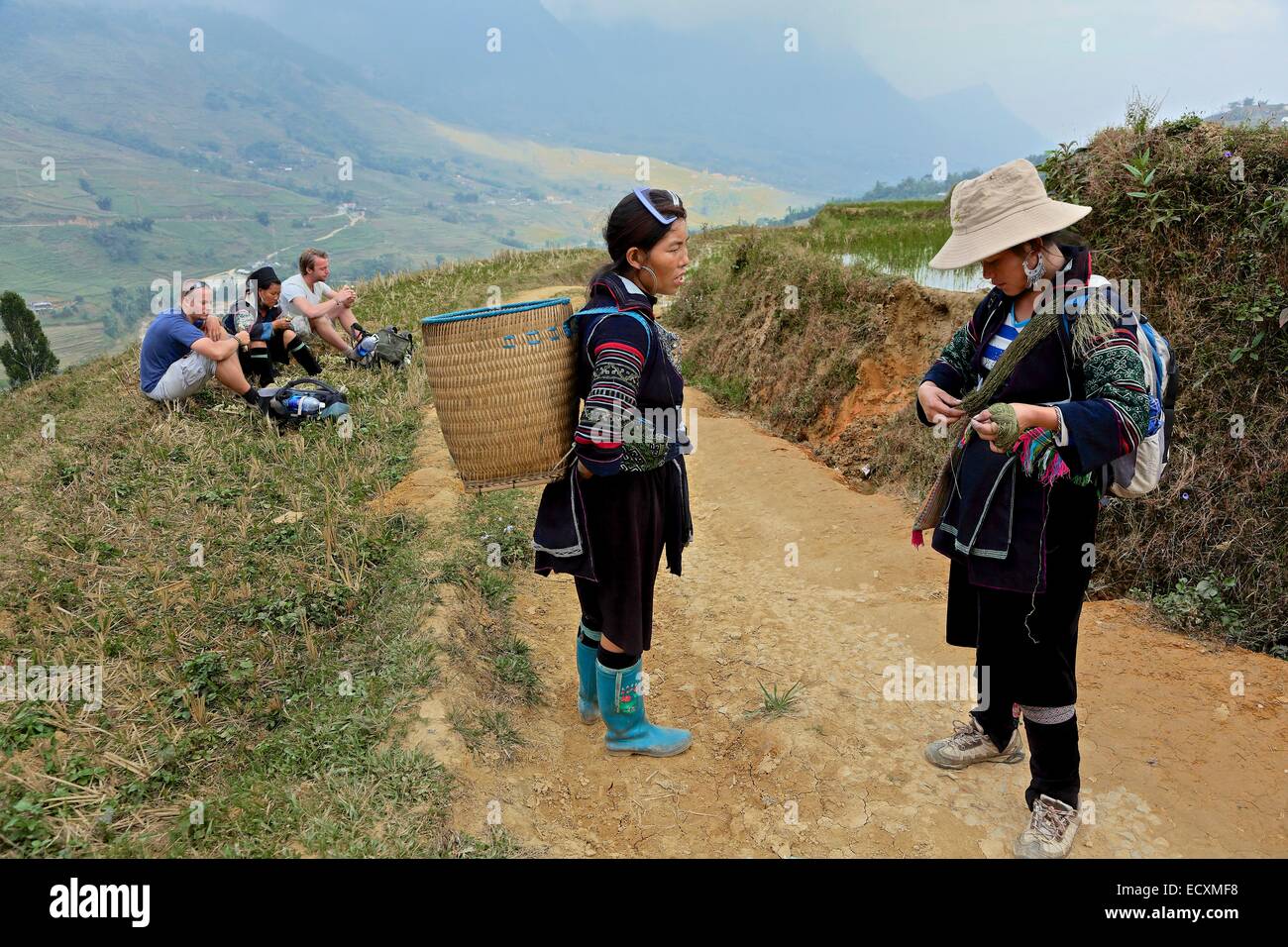 Deux femmes Hmong qui parlent avec des touristes en arrière-plan.Une femme ois tourne le chanvre main, l'autre est sur son chemin au marché de Sapa Banque D'Images