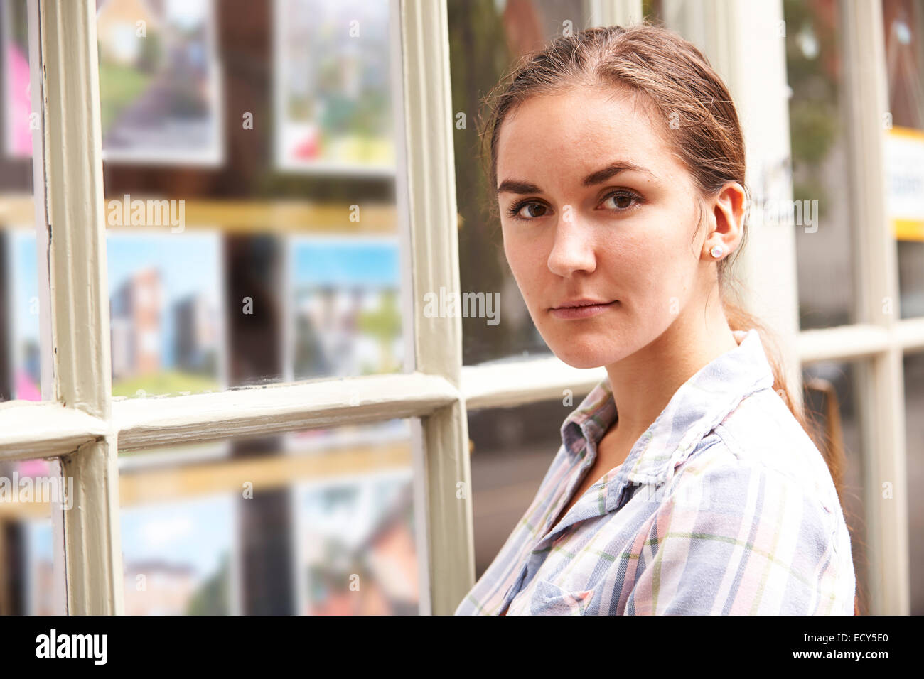 Déçu à la jeune femme à la fenêtre d'agents immobiliers Banque D'Images