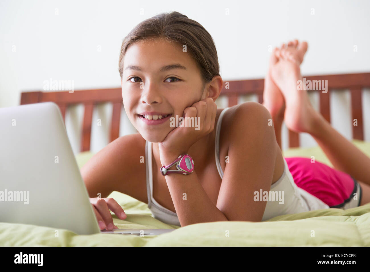 Mixed Race girl using laptop on bed Banque D'Images