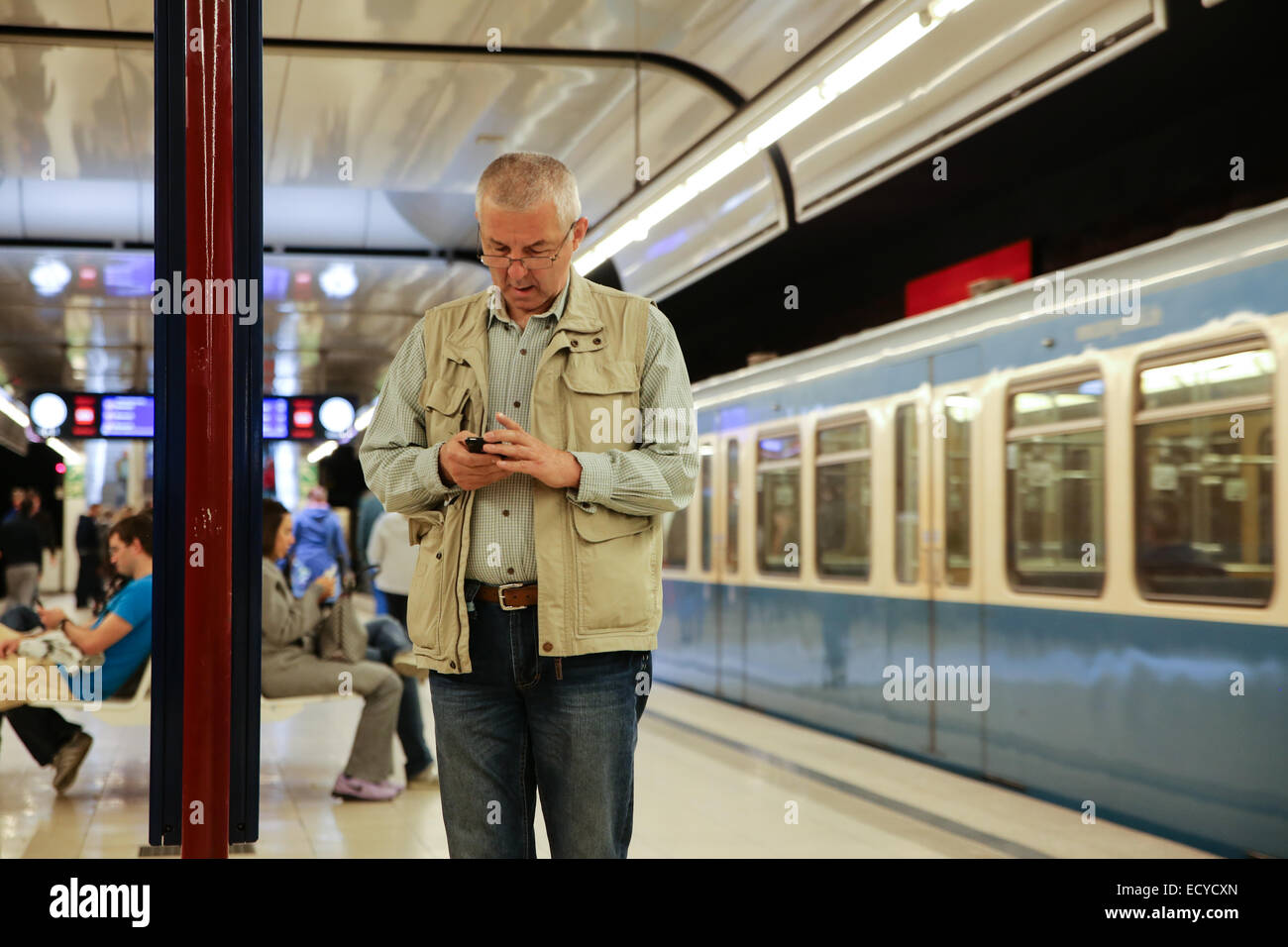 Vieil homme contrôle de téléphone cellulaire à l'intérieur gare allemagne europe Banque D'Images