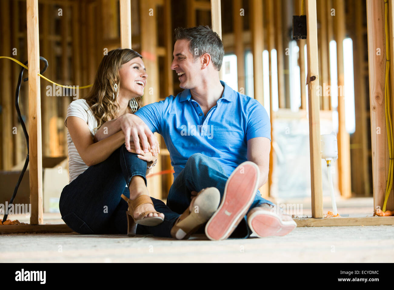 Caucasian couple sitting on floor in house under construction Banque D'Images