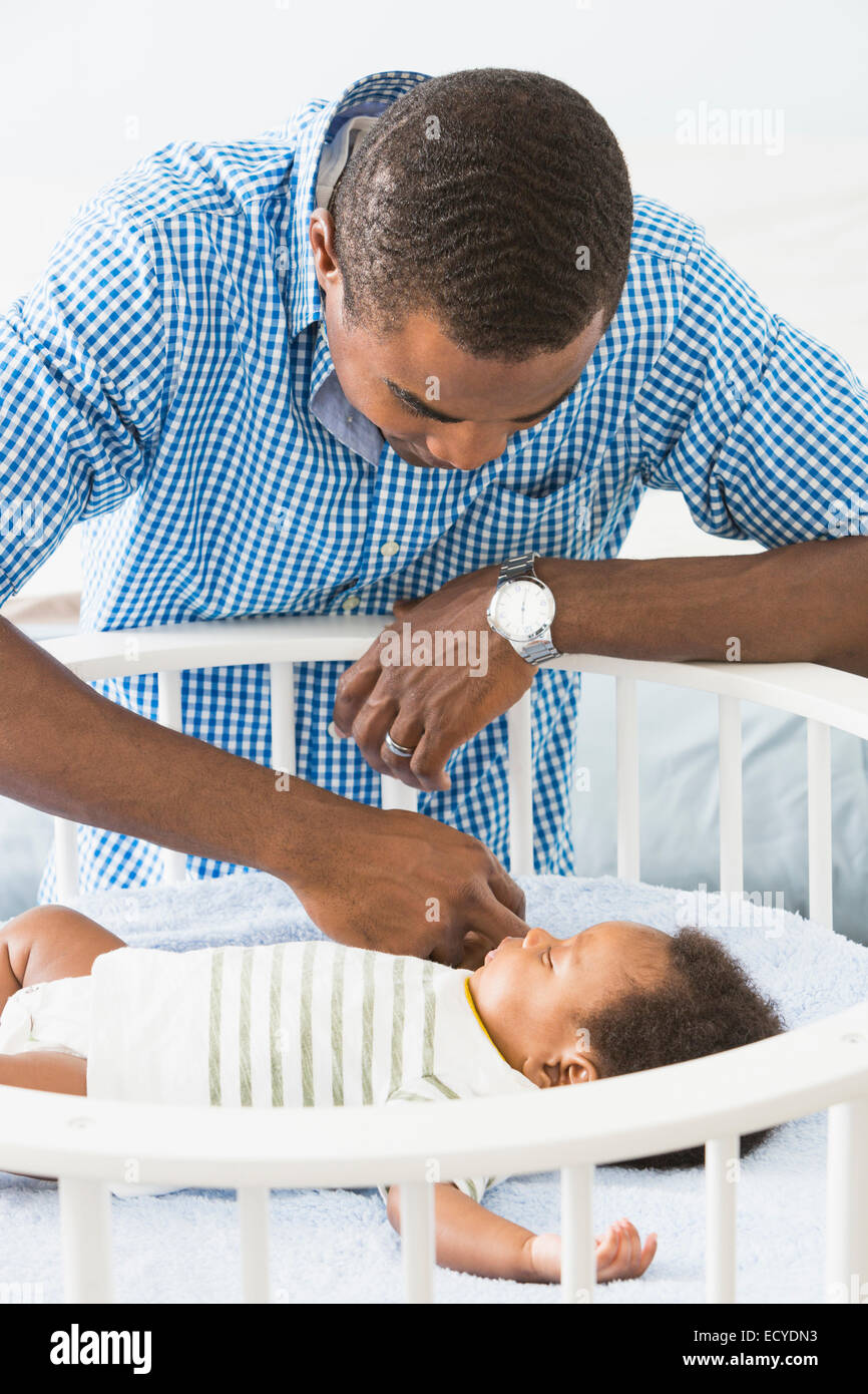 Père d'admirer bébé endormi dans son berceau Banque D'Images