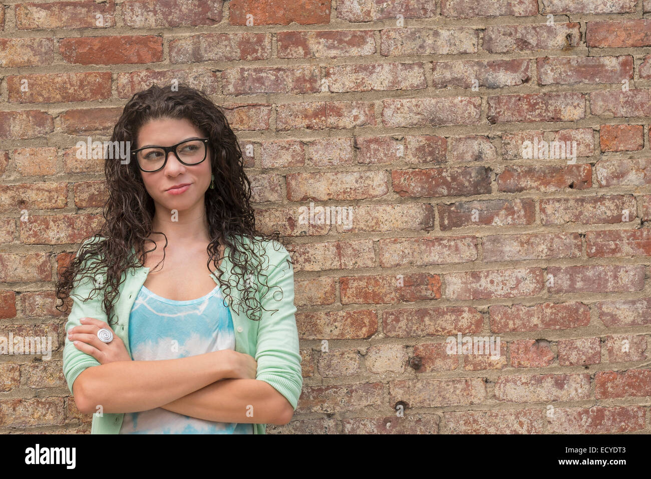 Pensive mixed race woman standing with arms crossed Banque D'Images
