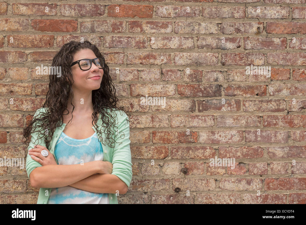Pensive mixed race woman standing with arms crossed Banque D'Images
